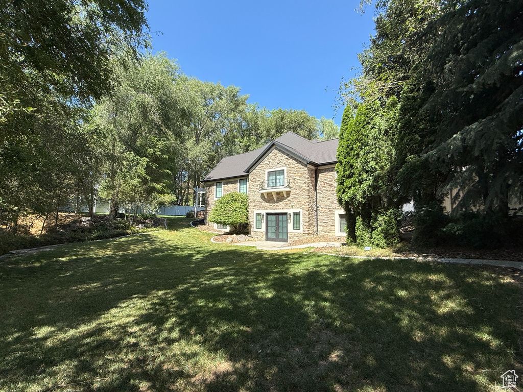 Back of house with stone siding and a yard