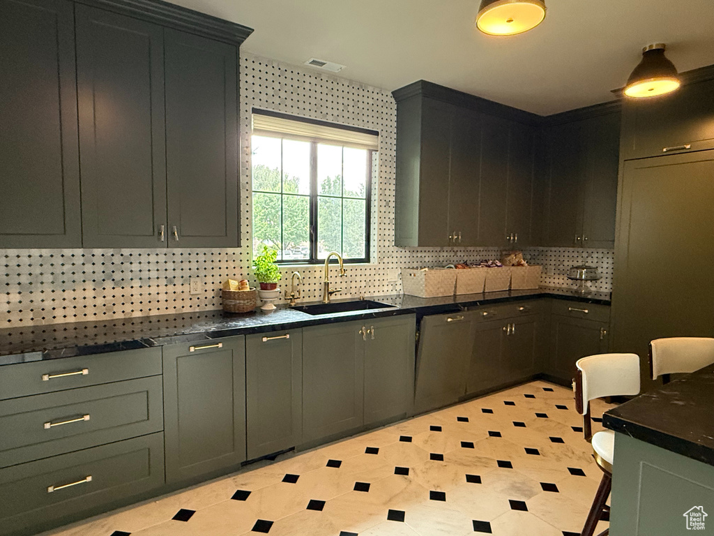 Kitchen featuring decorative backsplash, light floors, and dark stone counters