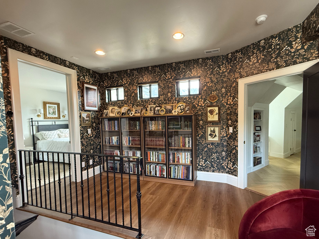 Sitting room with wallpapered walls, wood finished floors, and recessed lighting