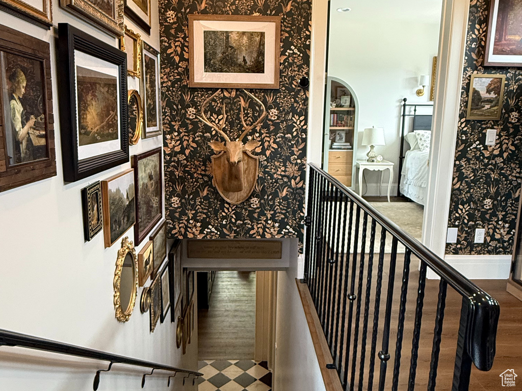 Staircase with wallpapered walls and wood finished floors