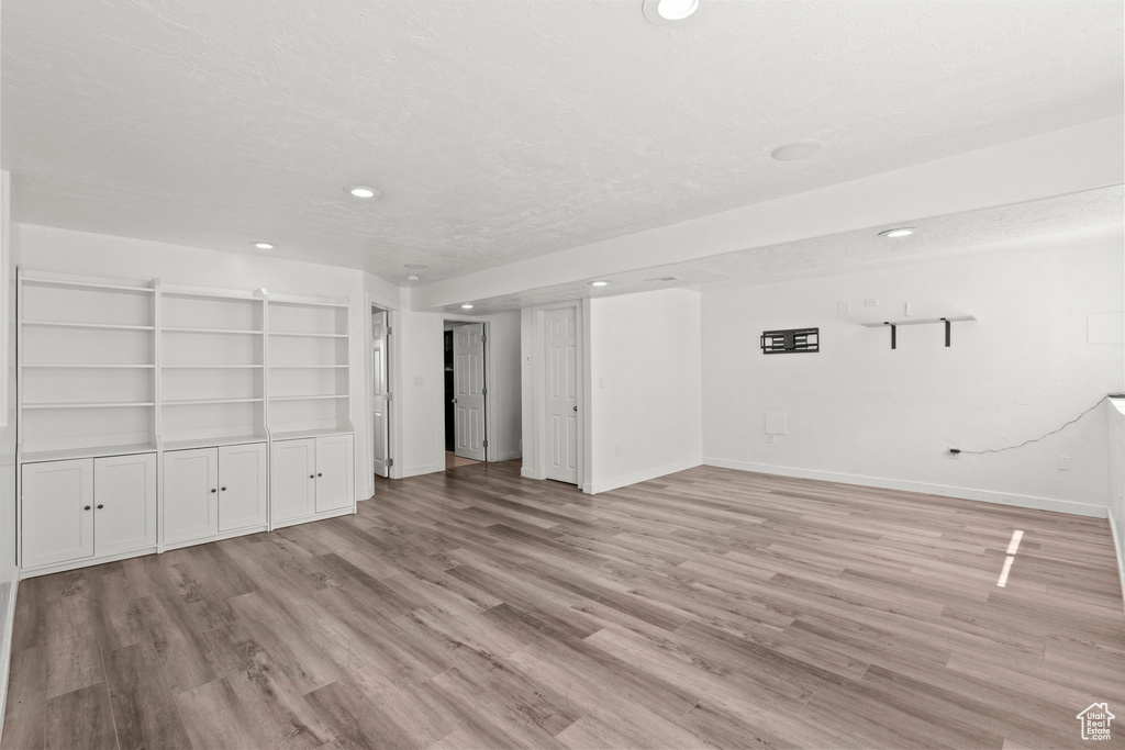 Unfurnished living room with light wood-type flooring, recessed lighting, and a textured ceiling