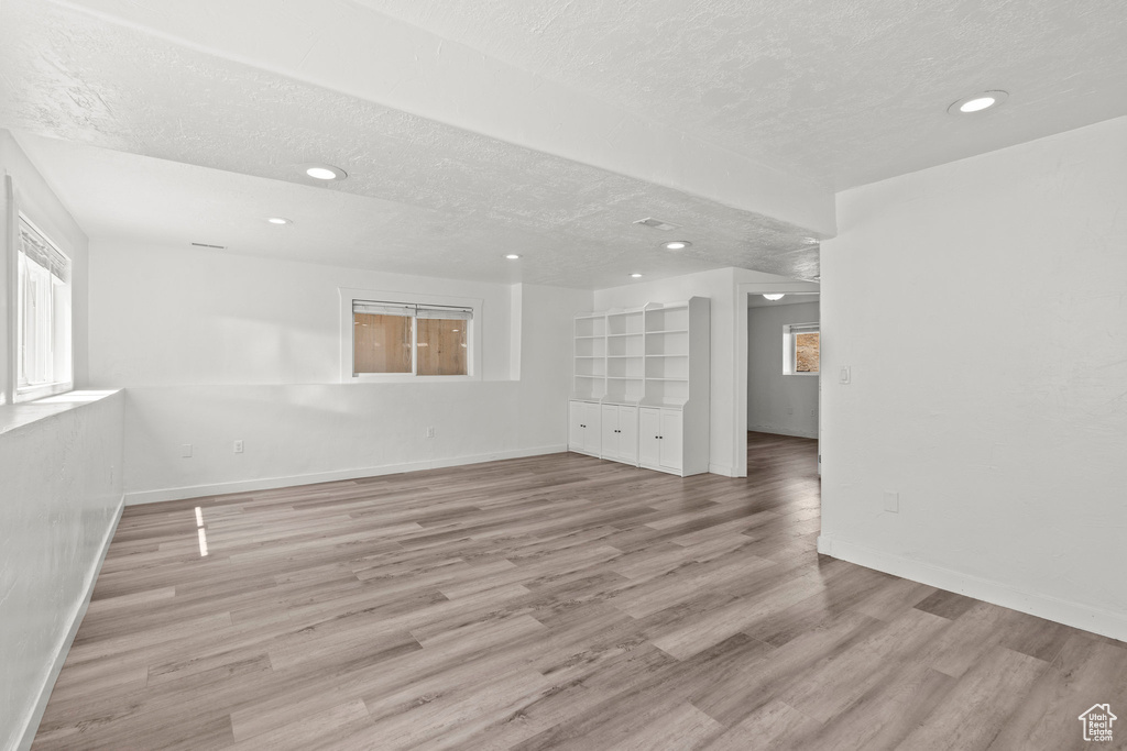 Empty room featuring light wood-style flooring, recessed lighting, and a textured ceiling
