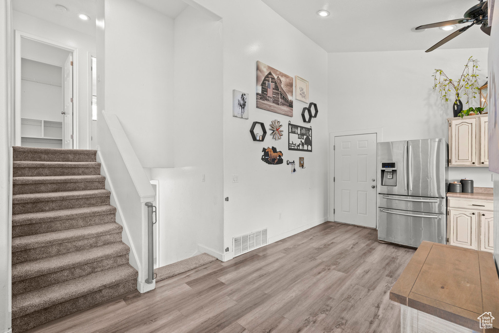 Kitchen featuring stainless steel fridge with ice dispenser, a ceiling fan, light wood-style flooring, light countertops, and recessed lighting