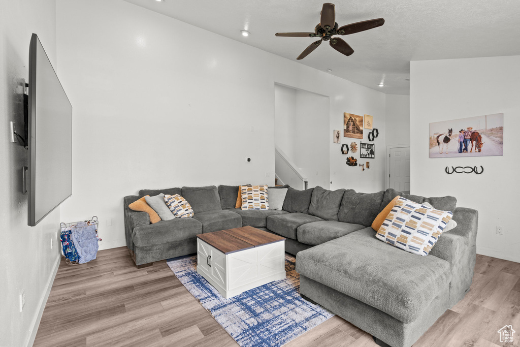 Living area featuring stairs, light wood finished floors, a ceiling fan, and recessed lighting