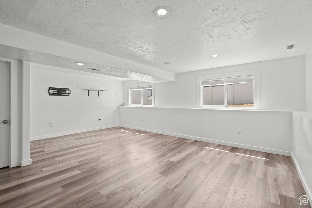 Unfurnished room featuring a textured ceiling, light wood-style flooring, and recessed lighting