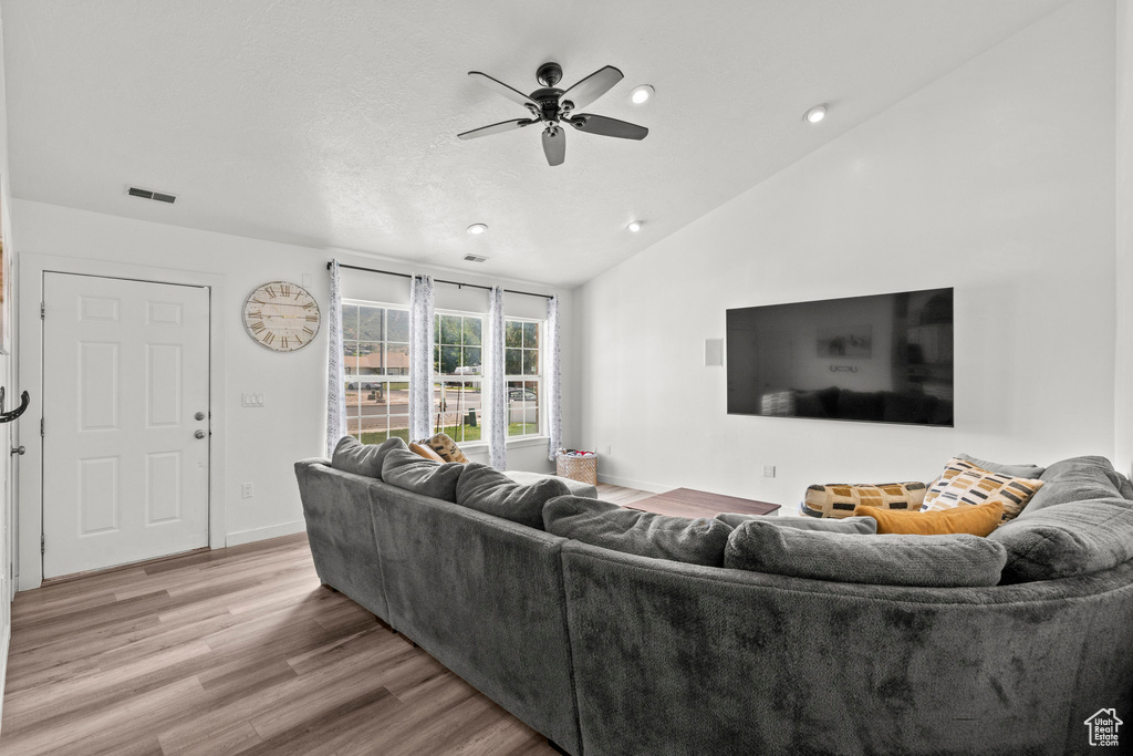 Living area with a ceiling fan, wood finished floors, vaulted ceiling, and recessed lighting