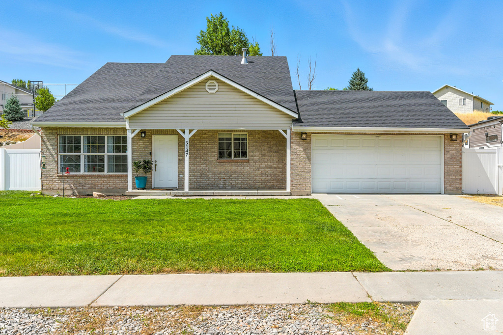 View of front of house with a garage, driveway, brick siding, and roof with shingles