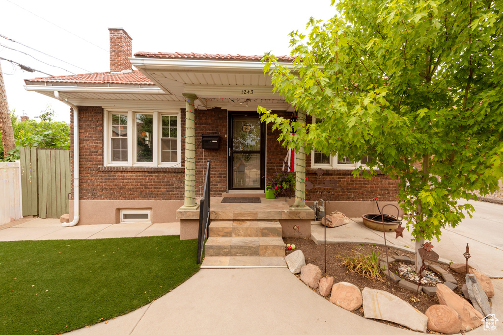 View of front facade featuring a chimney, brick siding, and a tile roof