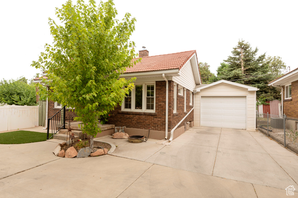 View of front of home featuring brick siding, a tiled roof, driveway, and a chimney