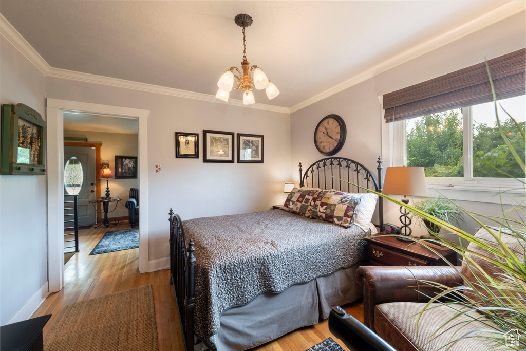 Bedroom with a chandelier, light wood-type flooring, and crown molding