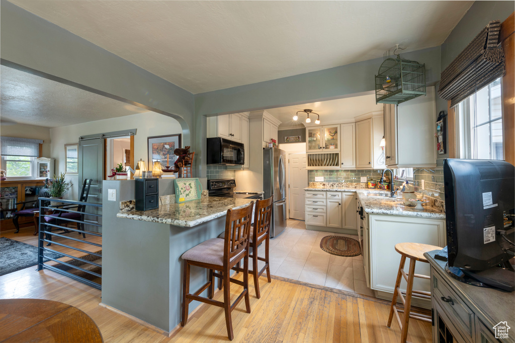 Kitchen with plenty of natural light, light stone counters, light wood-style flooring, and black microwave