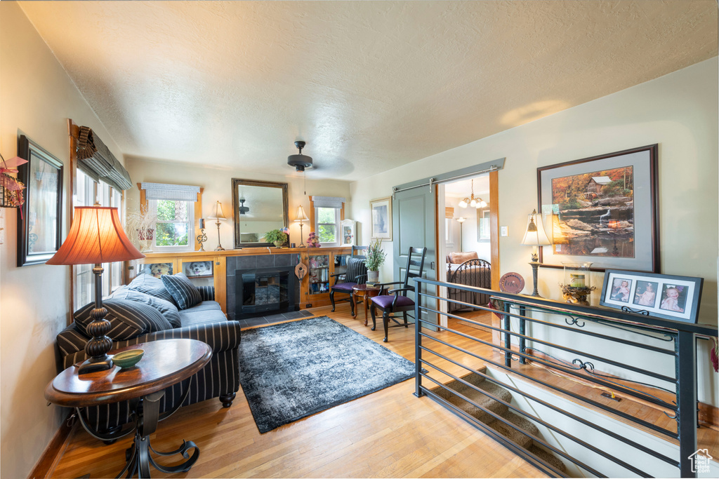Living area with wood finished floors, a tiled fireplace, and a textured ceiling
