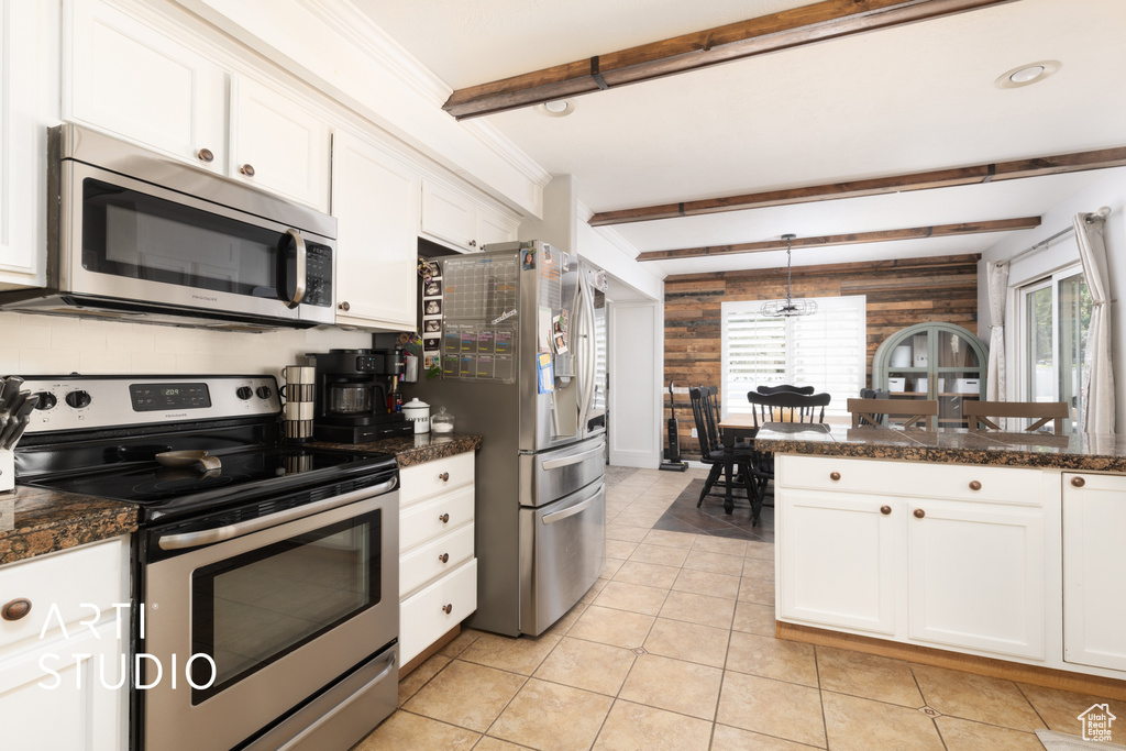 Kitchen with stainless steel appliances, beamed ceiling, plenty of natural light, white cabinets, and light tile patterned flooring