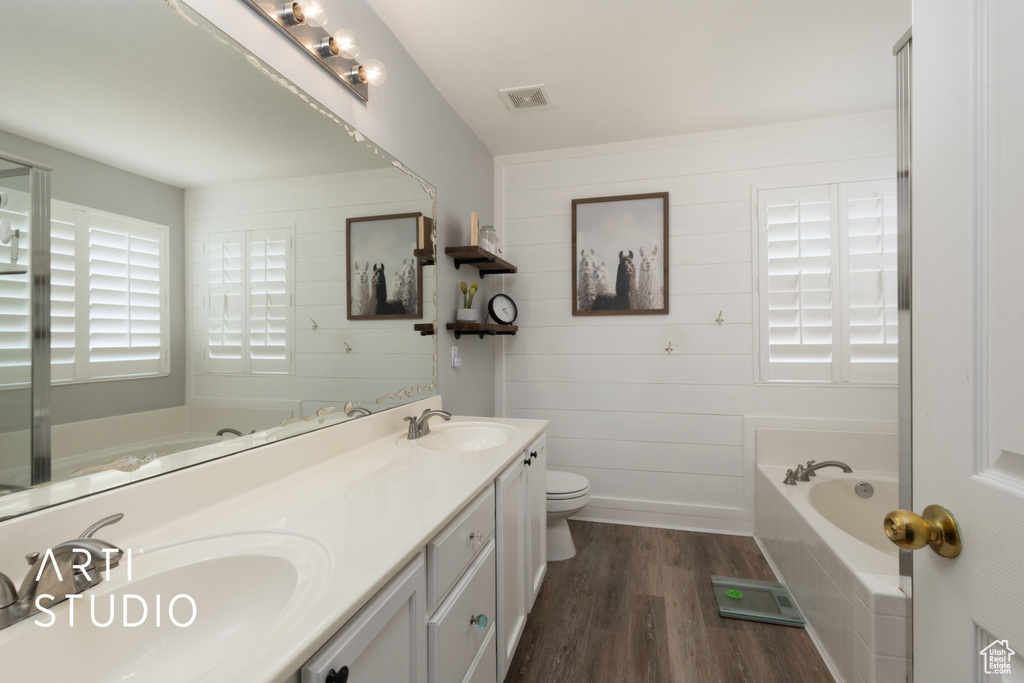 Full bath featuring a bath, wood finished floors, and double vanity