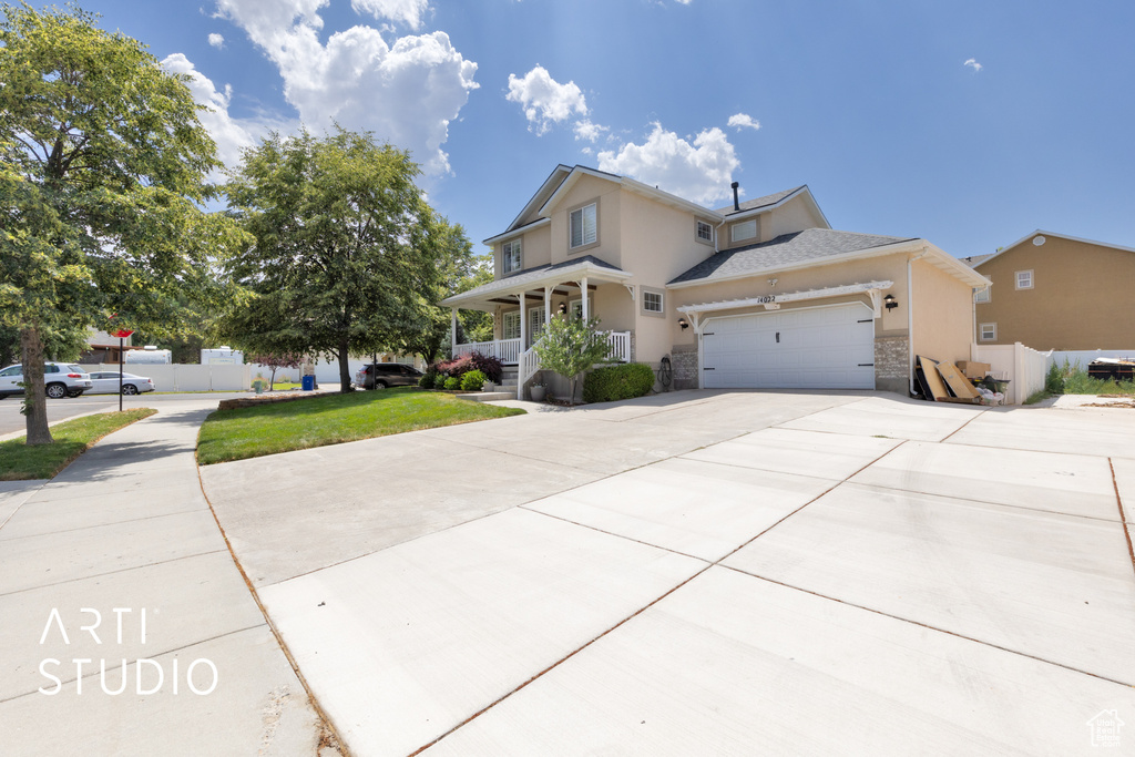 Traditional home with a porch, concrete driveway, a garage, stucco siding, and stone siding