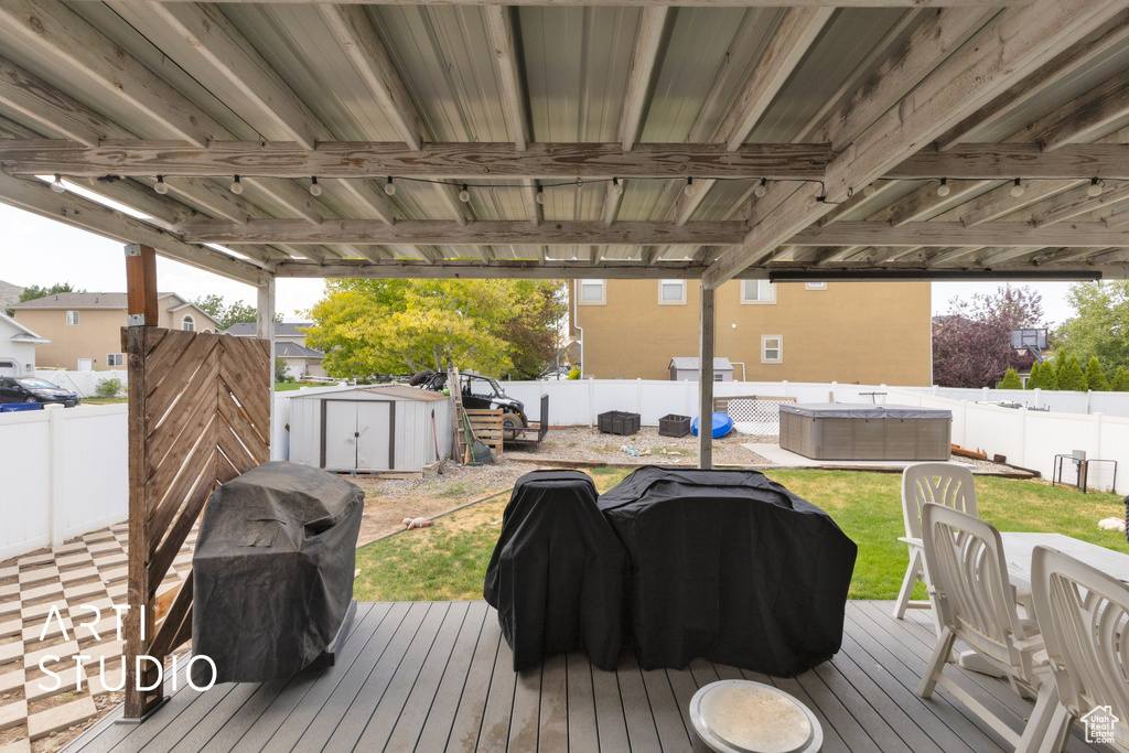 Deck with a storage unit, a fenced backyard, and area for grilling