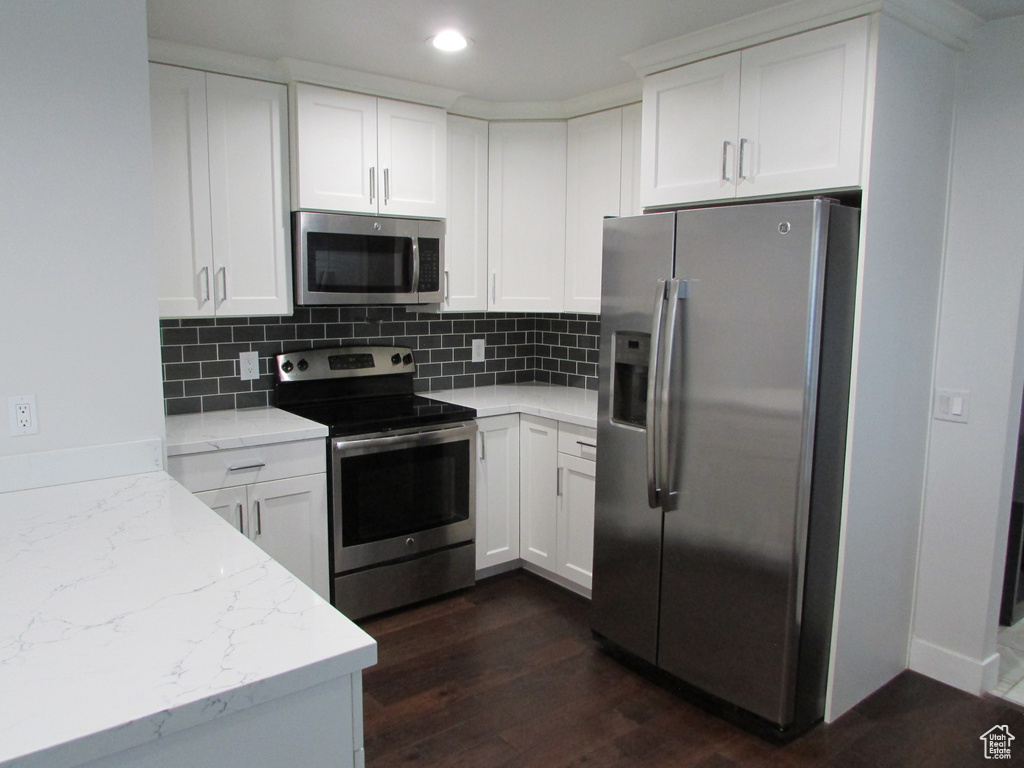 Kitchen featuring stainless steel appliances, backsplash, dark wood-style floors, white cabinetry, and recessed lighting