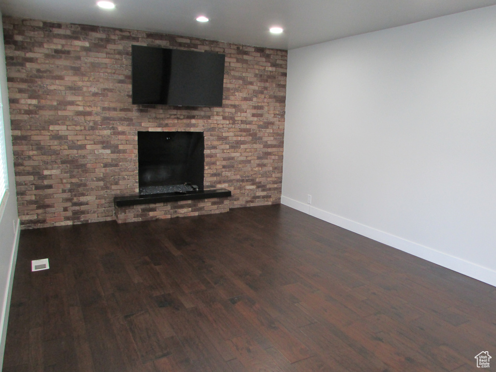 Unfurnished living room featuring dark wood-style floors, a fireplace, and recessed lighting