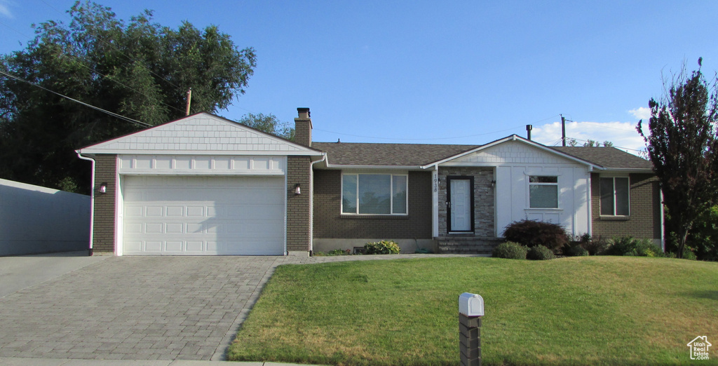 Single story home with an attached garage, a front yard, decorative driveway, a chimney, and brick siding
