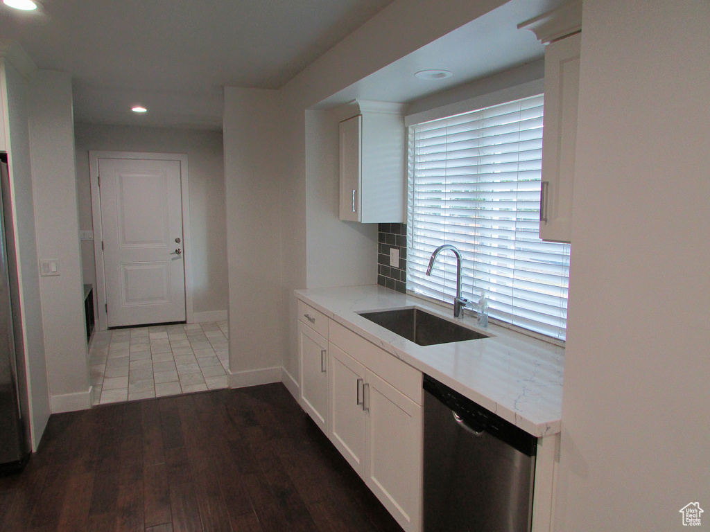 Kitchen featuring recessed lighting, stainless steel appliances, white cabinetry, wood finished floors, and tasteful backsplash