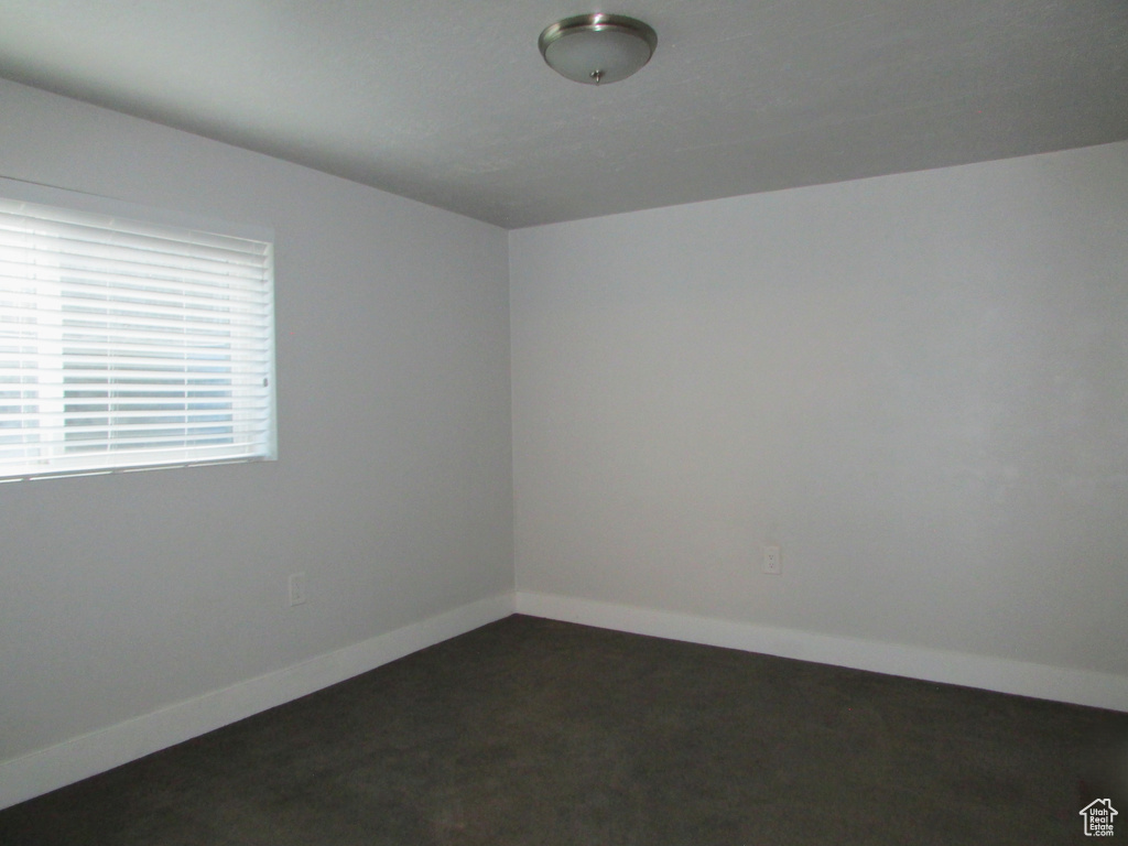 Unfurnished room with dark colored carpet and baseboards