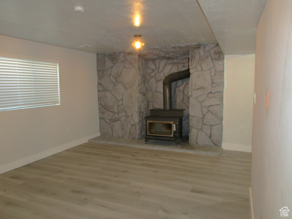 Unfurnished living room with a wood stove and wood finished floors