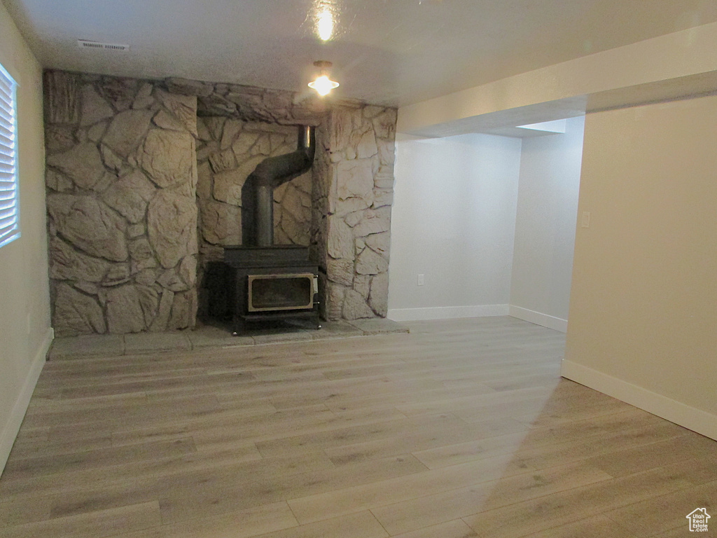 Unfurnished living room with wood finished floors and a wood stove