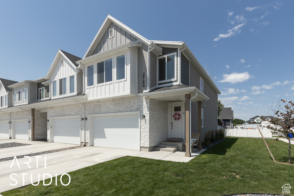 View of front facade with board and batten siding, an attached garage, concrete driveway, and brick siding