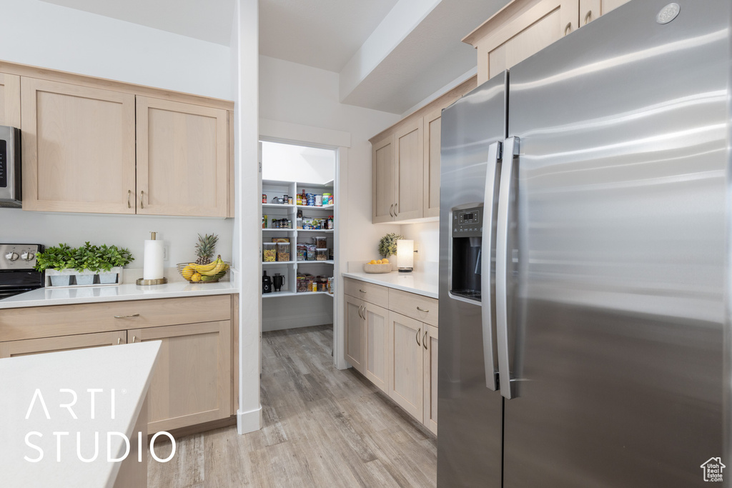 Kitchen featuring appliances with stainless steel finishes, light countertops, light wood finished floors, and light brown cabinets
