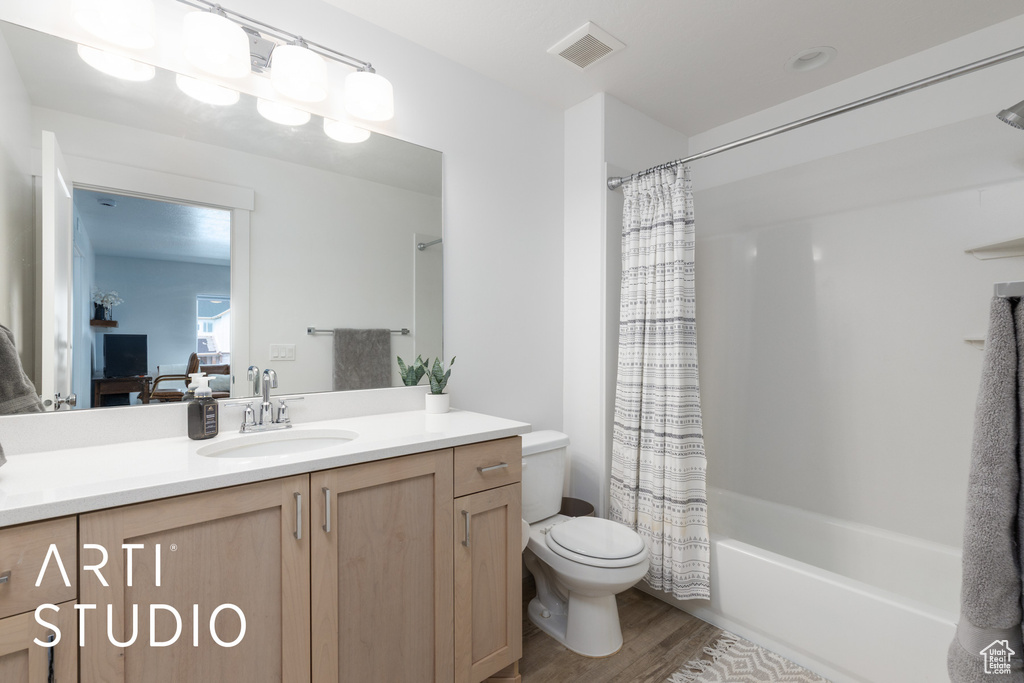 Bathroom featuring vanity, wood finished floors, and shower / bathtub combination with curtain