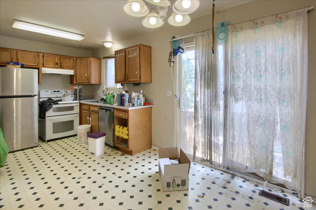 Kitchen with stainless steel appliances, healthy amount of natural light, light countertops, and brown cabinets