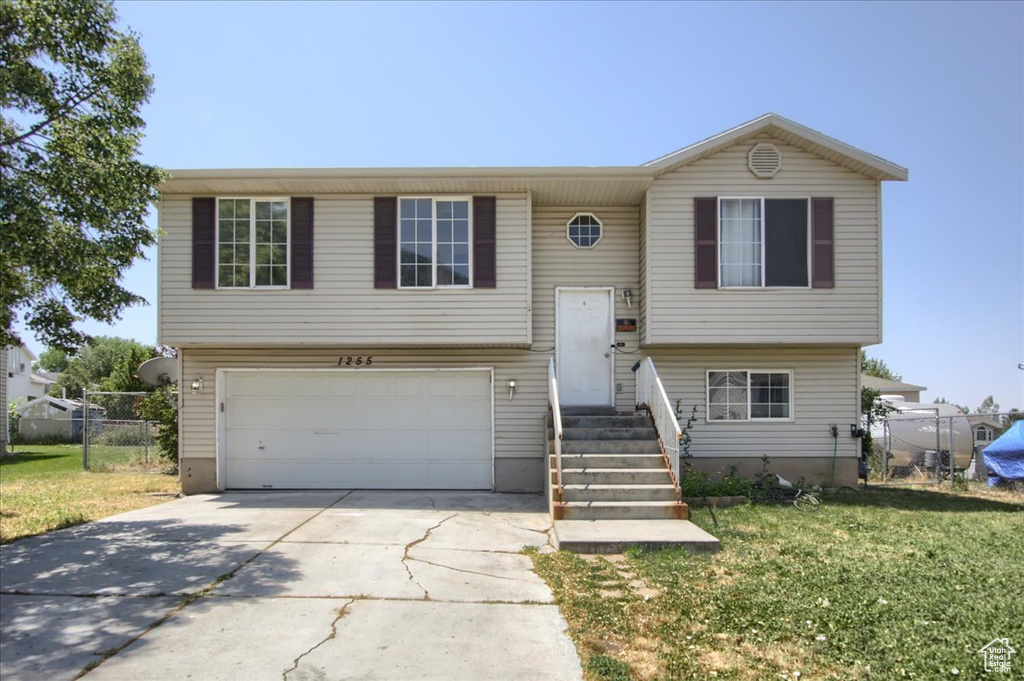 Bi-level home featuring concrete driveway and an attached garage