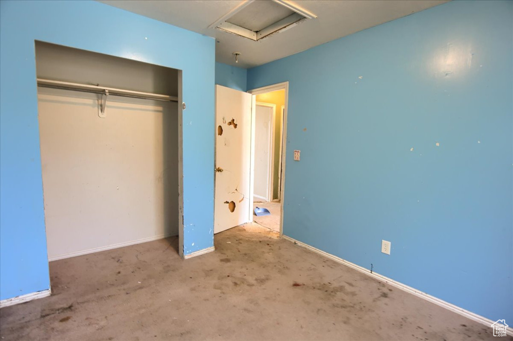 Unfurnished bedroom featuring a closet and attic access