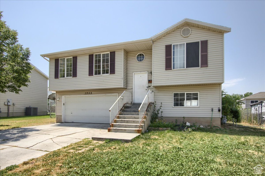 Bi-level home featuring driveway, an attached garage, and a front yard