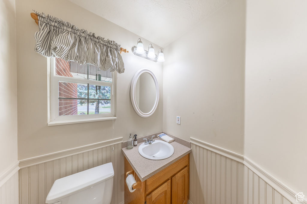 Half bathroom with vanity, a wainscoted wall, and a decorative wall