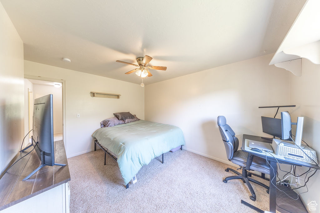 Carpeted bedroom featuring ceiling fan and an office area