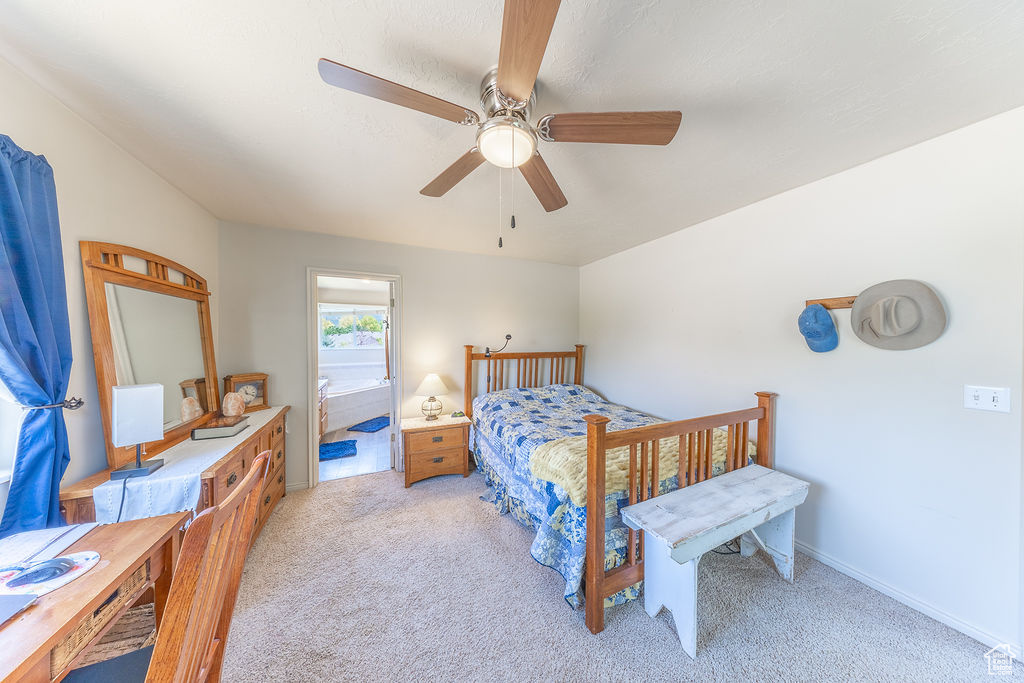 Bedroom featuring light carpet, ensuite bathroom, and a ceiling fan