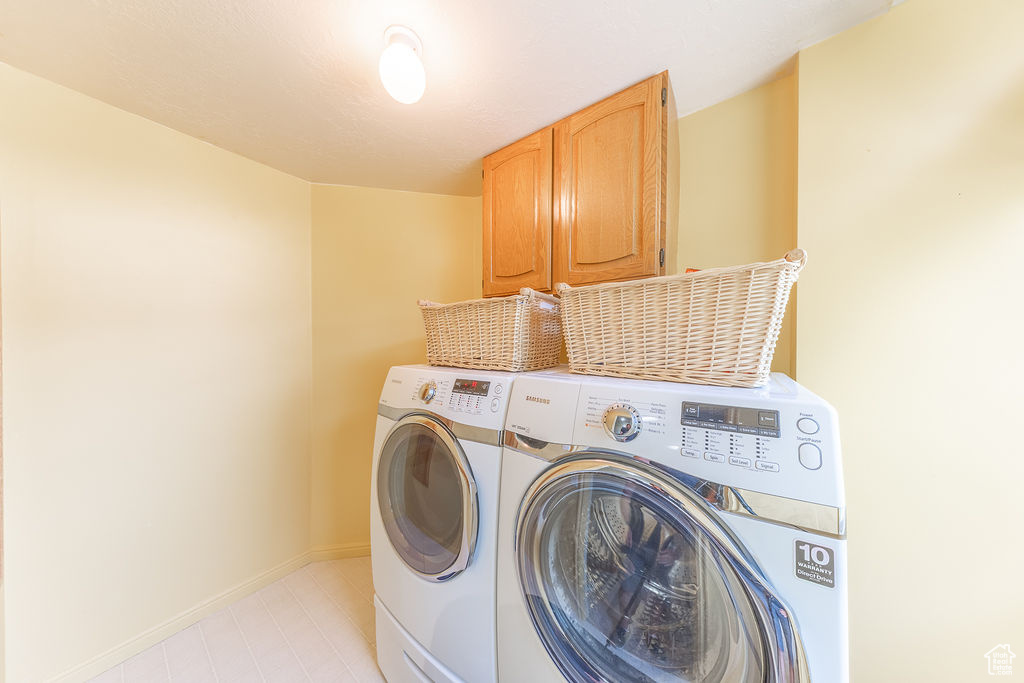 Laundry room with cabinet space, washer and clothes dryer, and light tile patterned floors