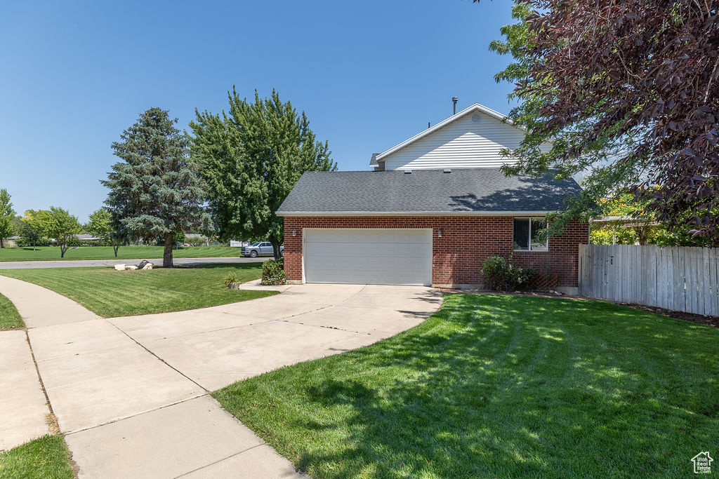 View of side of home featuring roof with shingles, brick siding, a garage, and driveway