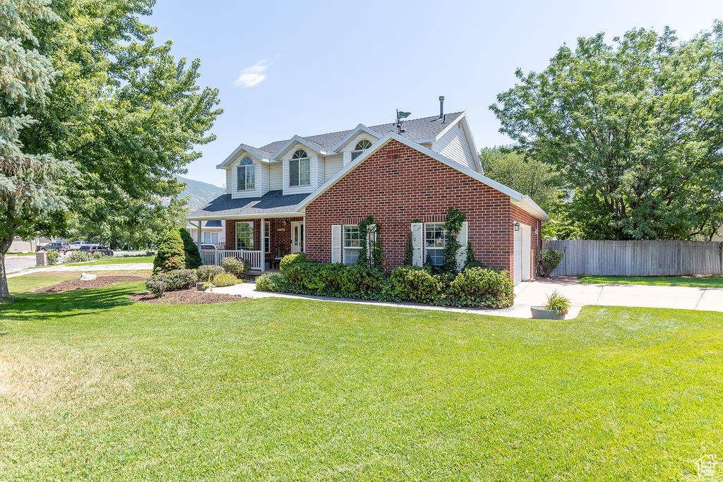 View of front of home with concrete driveway, a garage, brick siding, and a porch