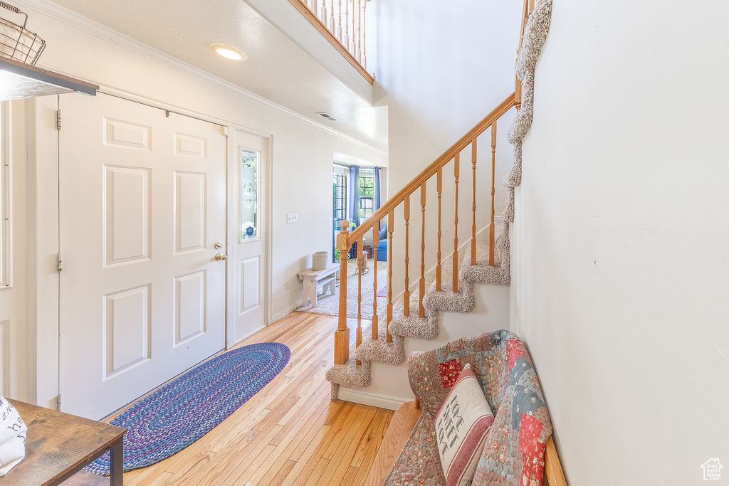 Foyer entrance featuring wood-type flooring, stairs, ornamental molding, and recessed lighting