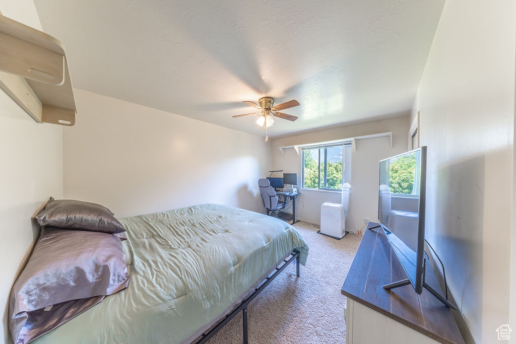 Bedroom with light colored carpet and a ceiling fan