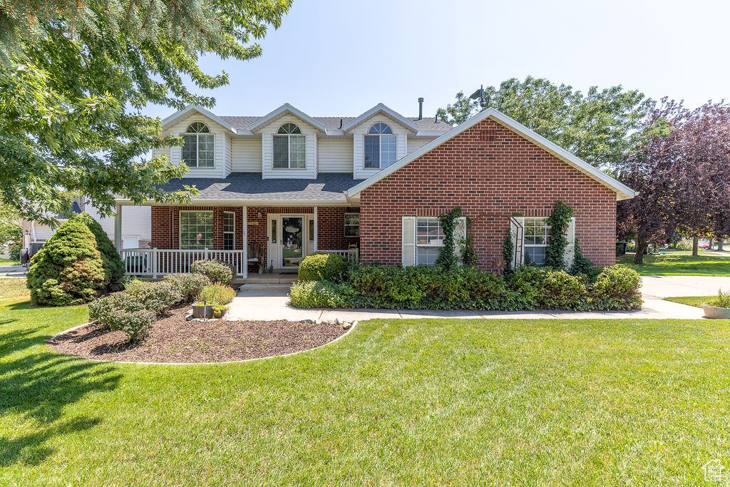 View of front of house with brick siding, a front yard, and a porch