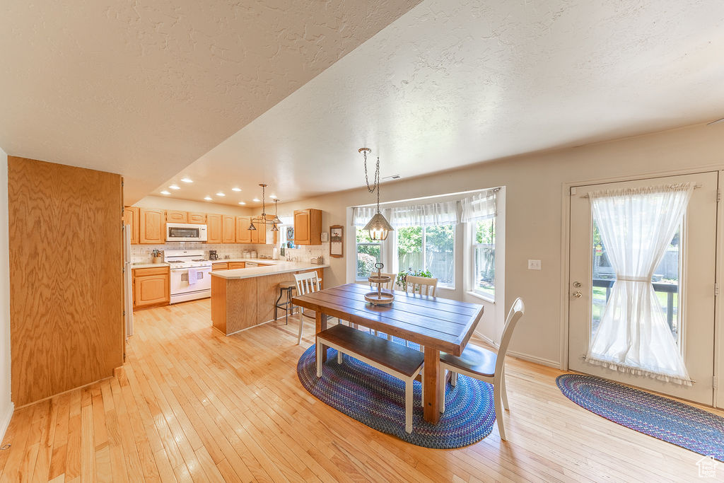 Dining room with a textured ceiling, light wood-style floors, and recessed lighting