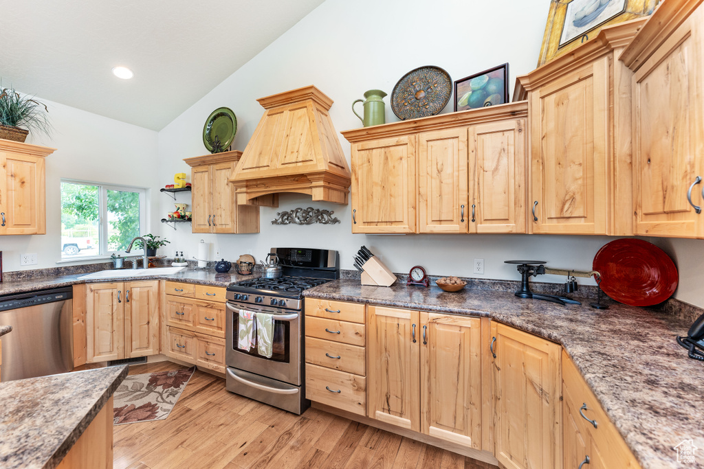 Kitchen featuring light brown cabinets, stainless steel appliances, custom range hood, high vaulted ceiling, and recessed lighting