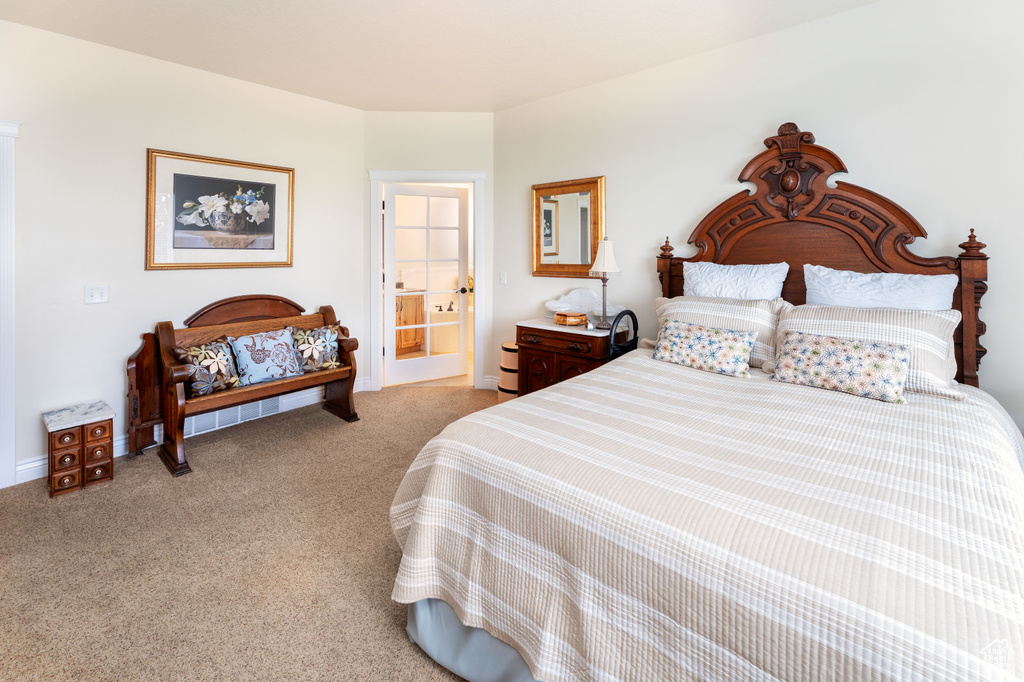 Bedroom featuring light colored carpet and ensuite bathroom
