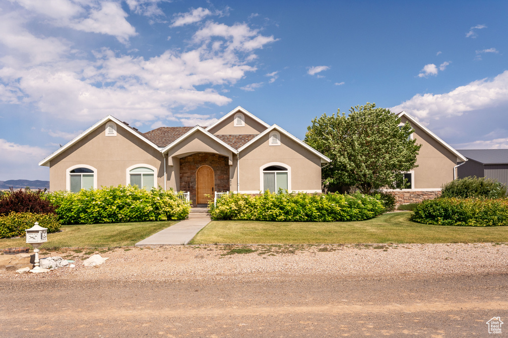 View of front of house featuring stone siding, a front yard, and stucco siding
