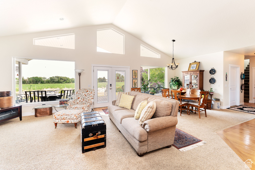 Living area featuring french doors, wood finished floors, a chandelier, and high vaulted ceiling