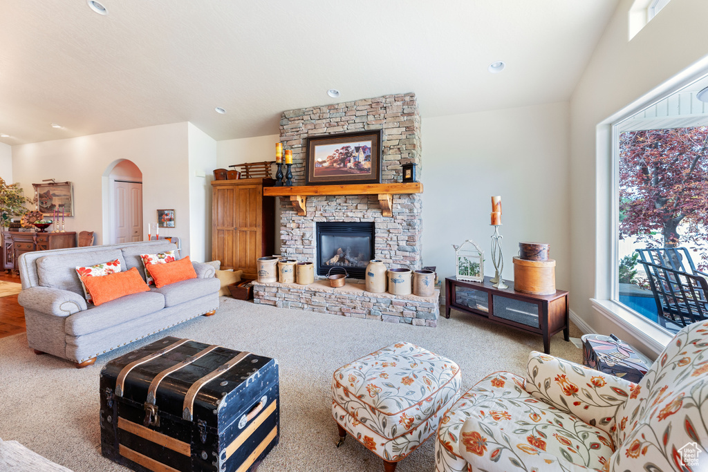 Carpeted living area with arched walkways, a fireplace, and recessed lighting