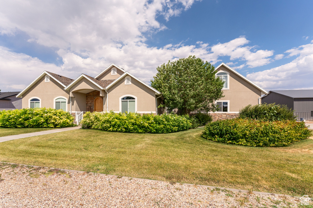 View of front of home featuring stone siding, stucco siding, and a front yard